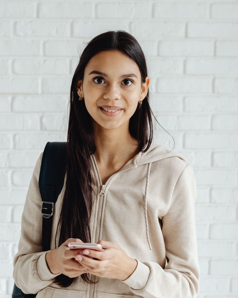 Woman smiling at the camera with her phone in hand