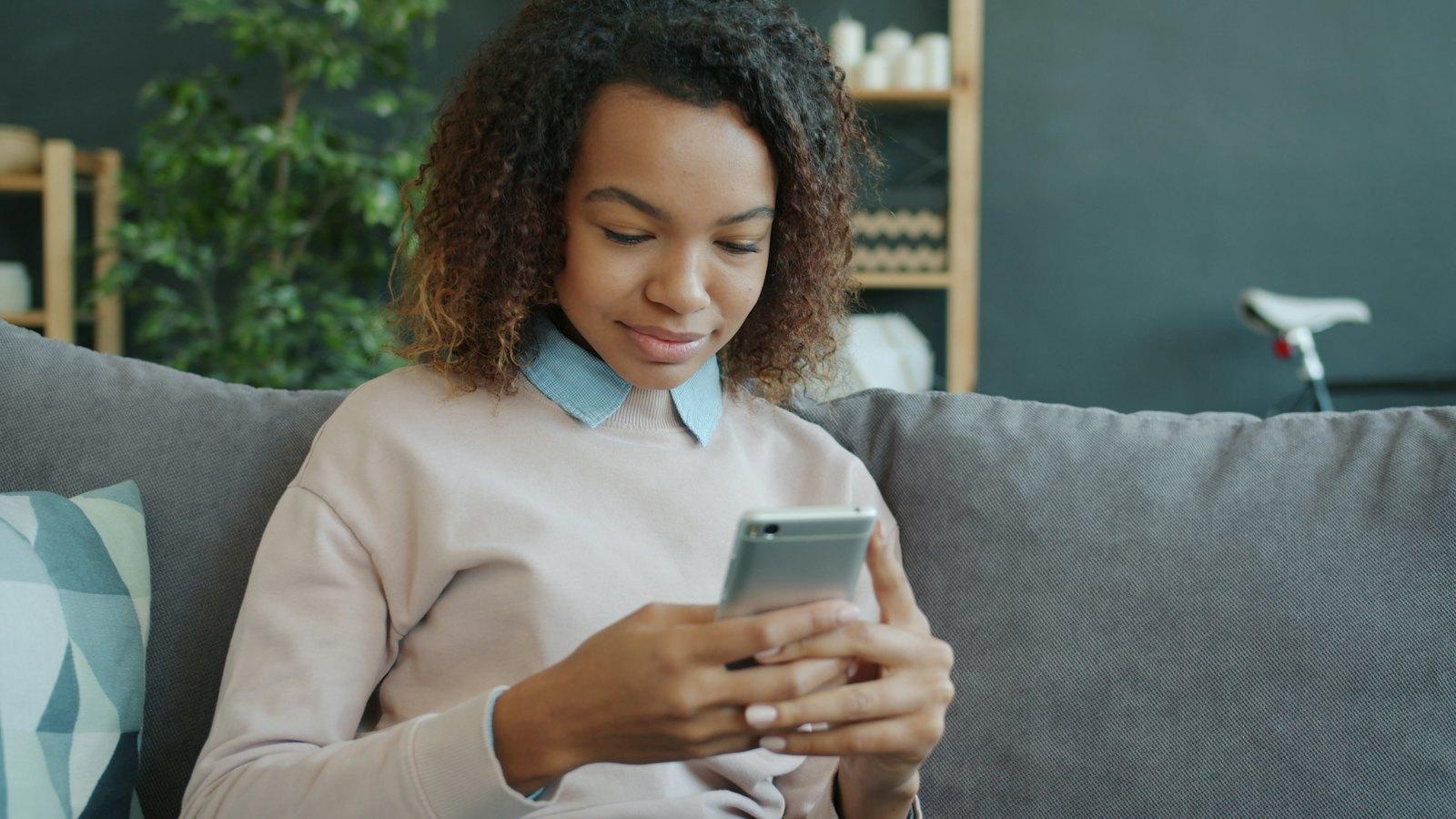 Woman smiling at a message at home